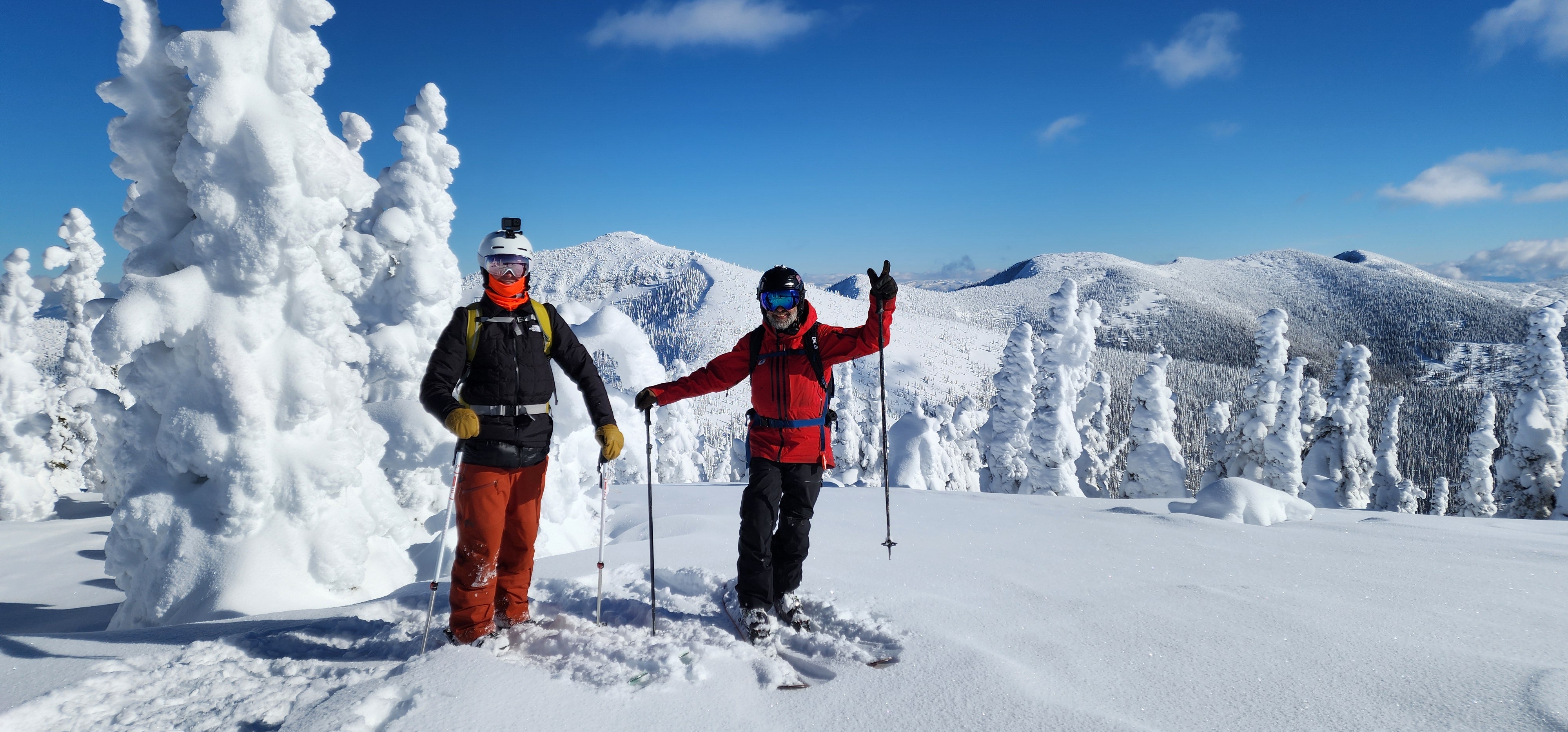 A Selkirk Powder client and Chief Guide Ken Barrett, on Mt Atlasta with the rest of SPC cat skiing terrain, Atlasta-Casey, laying in the background