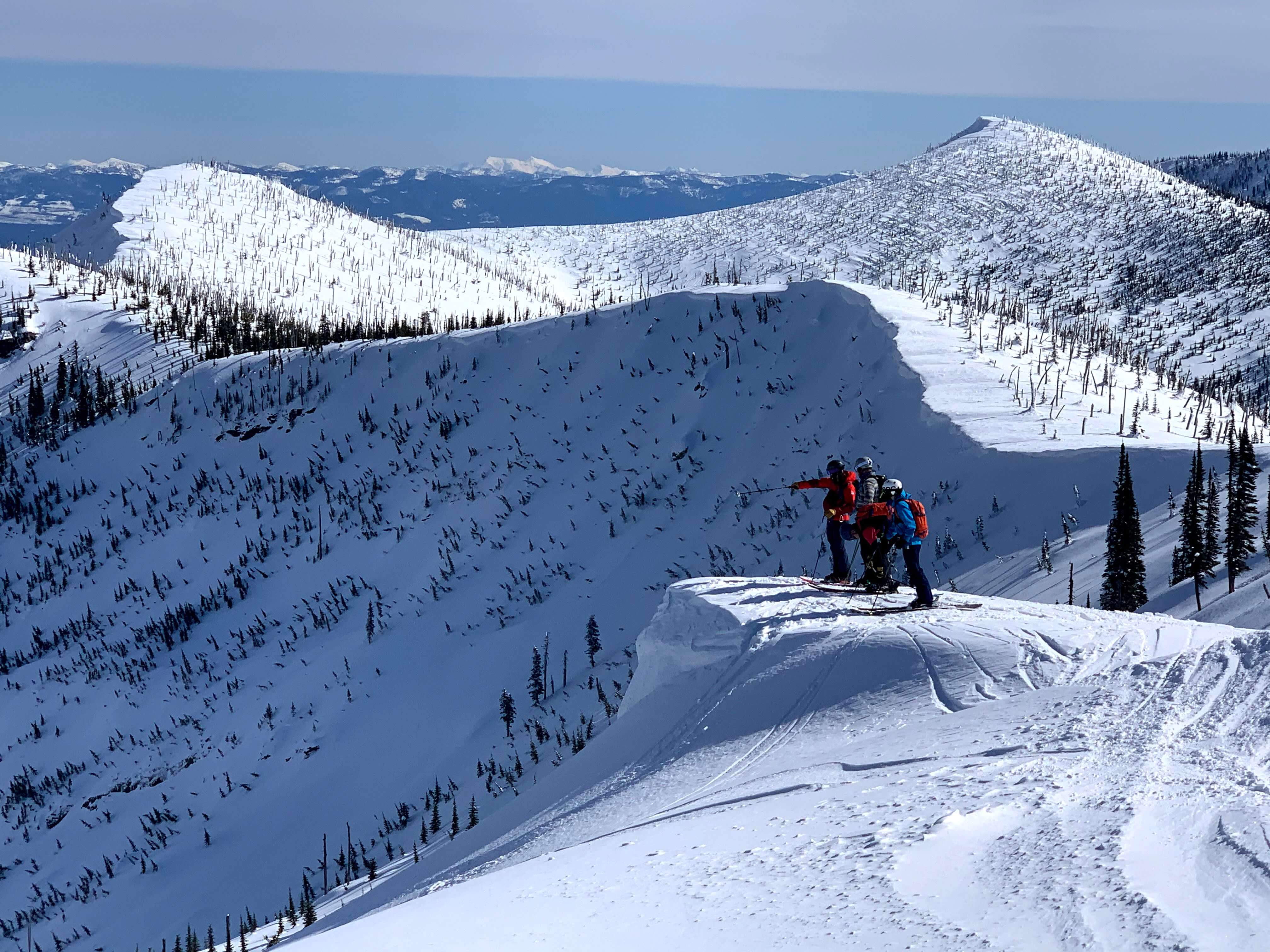 A group surveys backcountry ridges & terrain in Idaho's Selkirk Mountains