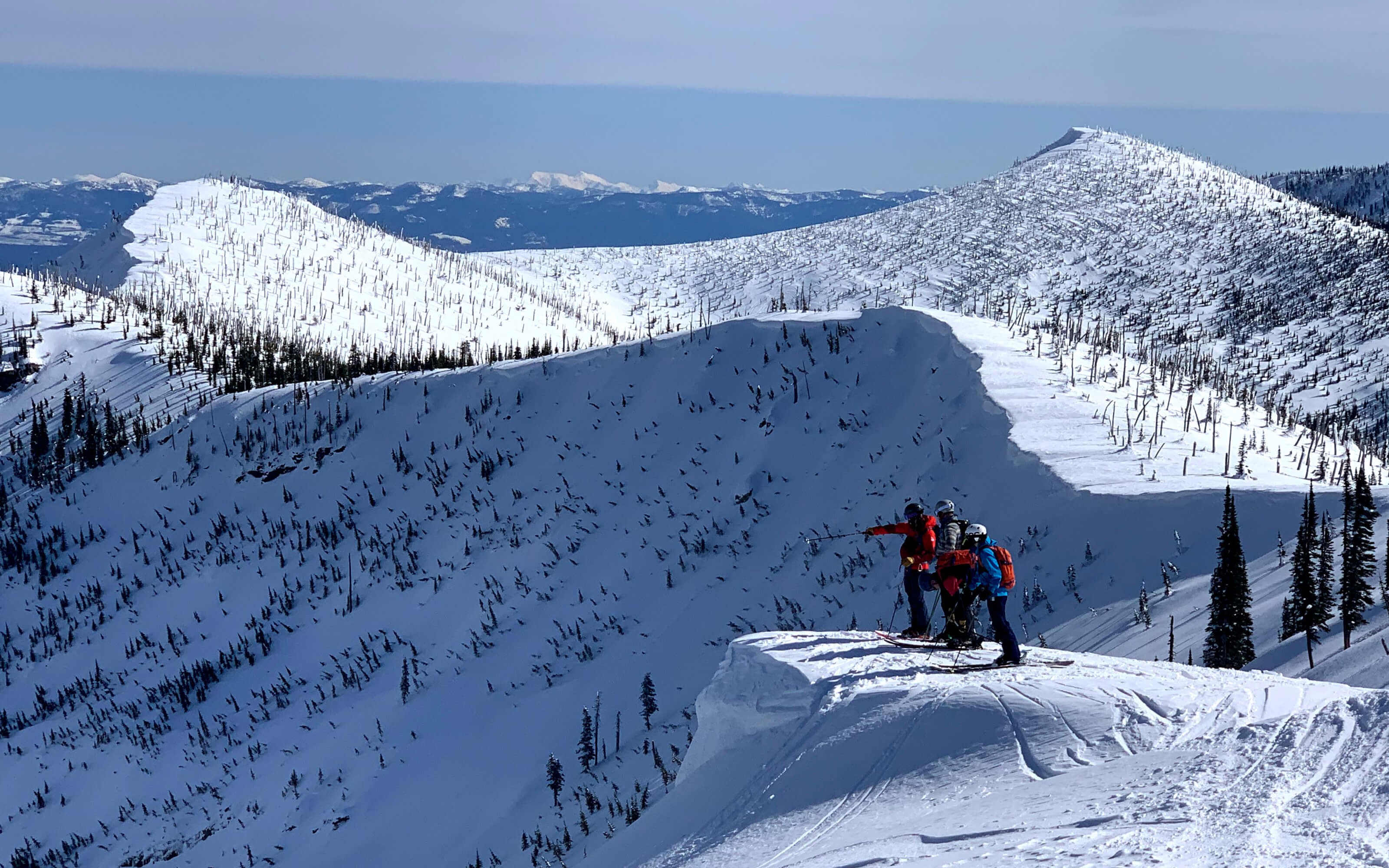 Skiers survey backcountry ridges and bowls in Idaho’s Selkirk Mountains