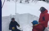 backcountry skiers in a snowpit talking