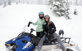 Two ladies smiling on a snowmobile